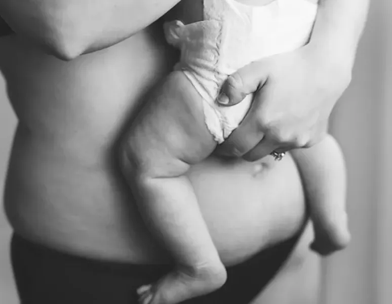 A constipated postpartum mom holding a baby.