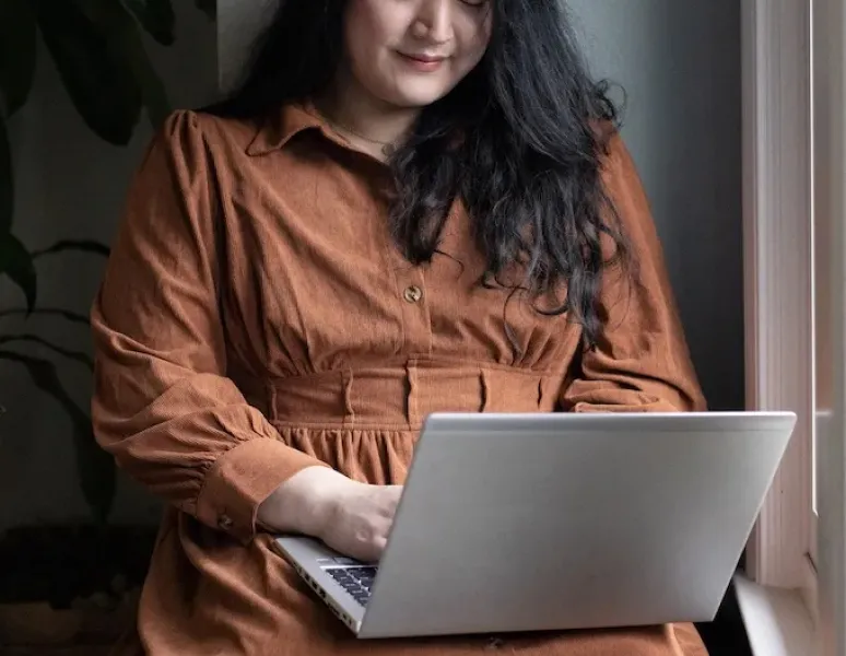 A trans, non-binary person looking for pelvic floor PT on their laptop.