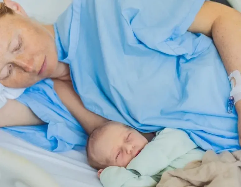 A postpartum athlete in the hospital with her newborn.