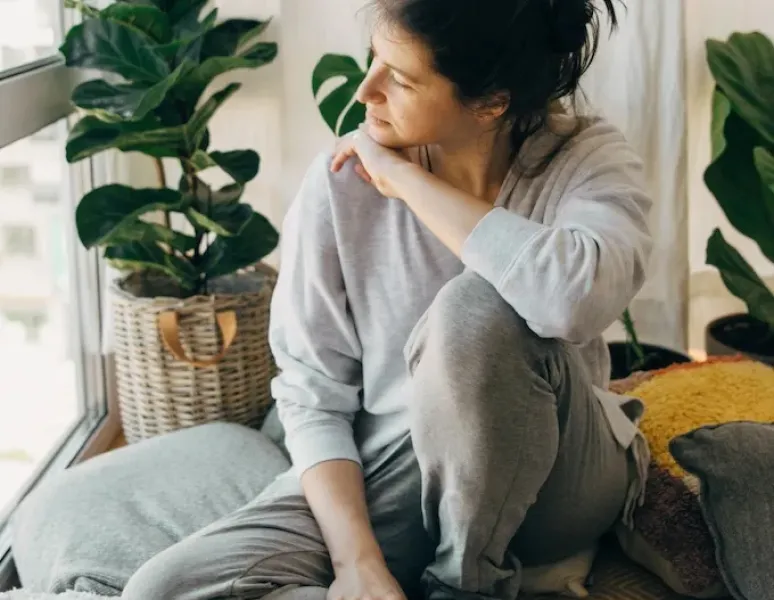 A woman sitting and staring out the window for a story on medical gaslighting and pelvic pain.