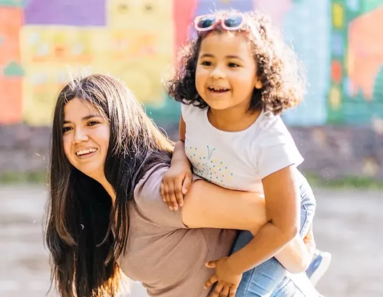 A woman with MSK issues carrying her school age daughter on her back.
