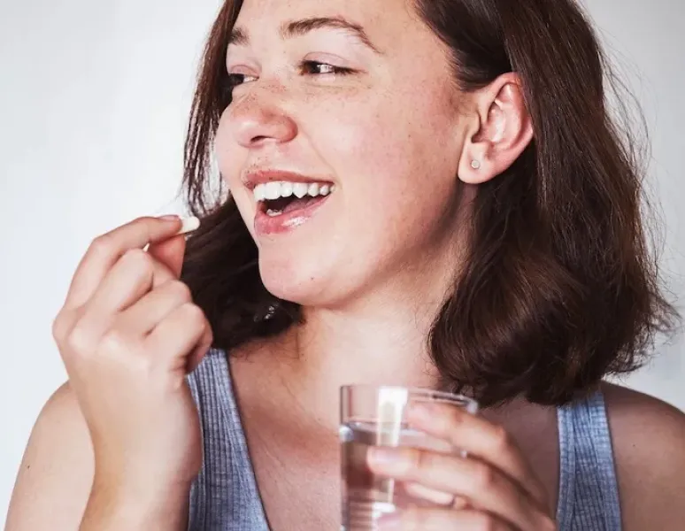 A young woman taking a birth control pill.