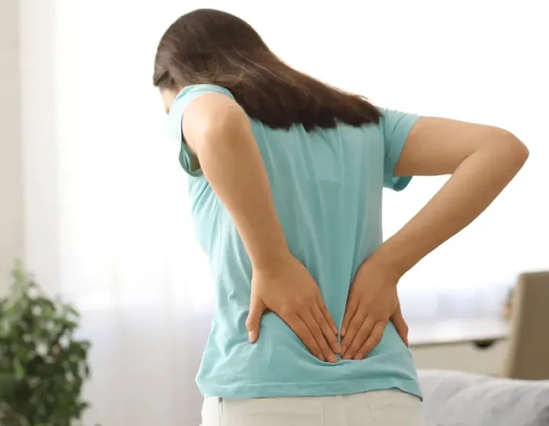 Woman holding her back symbolizing musculoskeletal pain.