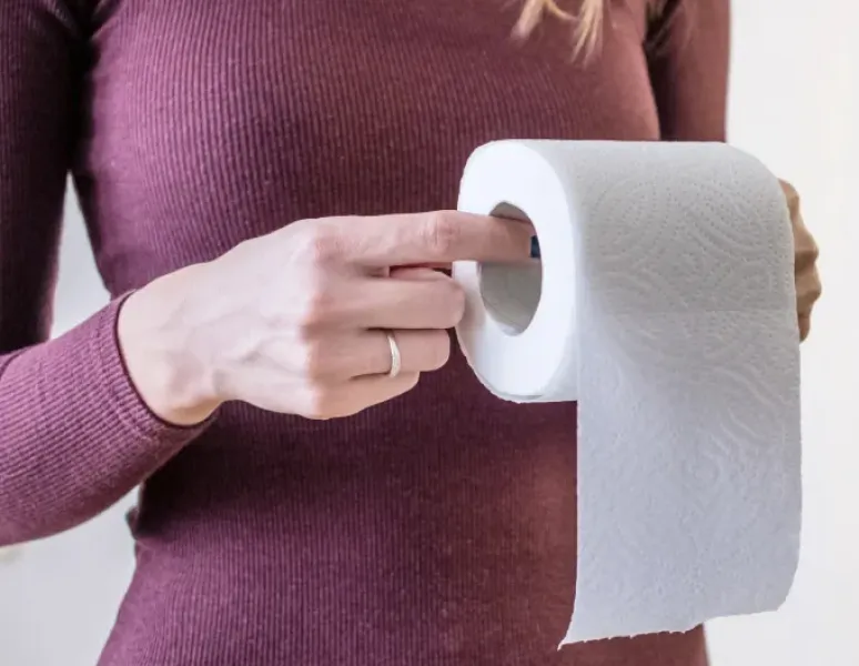 Woman holding a roll of toilet paper representing constipation from GLP-1 medication.
