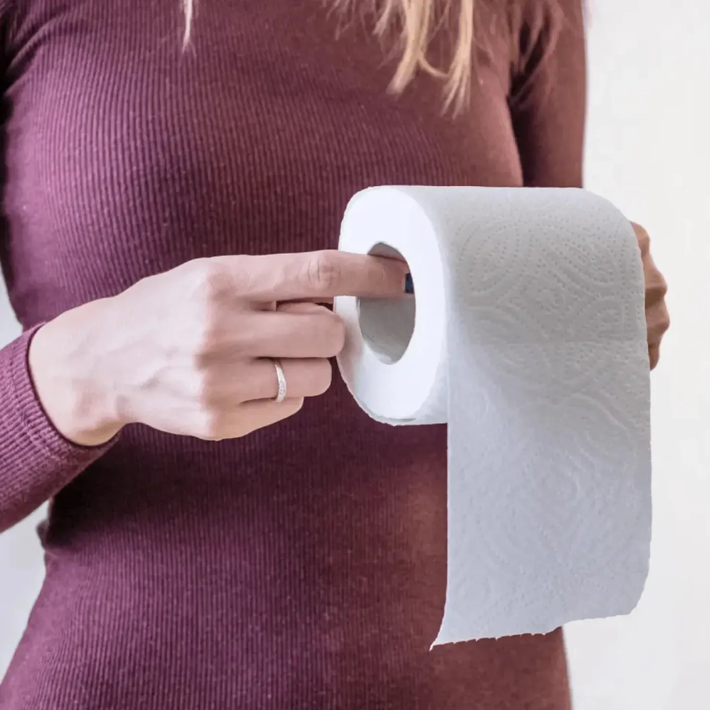 Woman holding a roll of toilet paper representing constipation from GLP-1 medication.