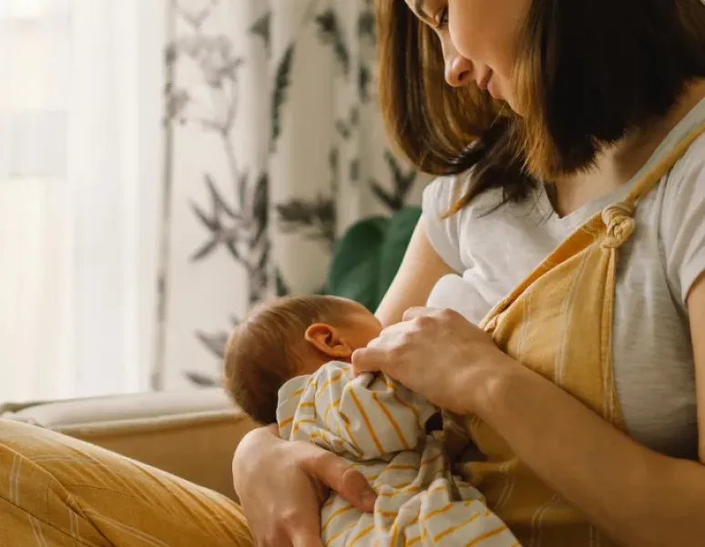Lactating woman breastfeeding a newborn baby using an IBCLC recommended hold.