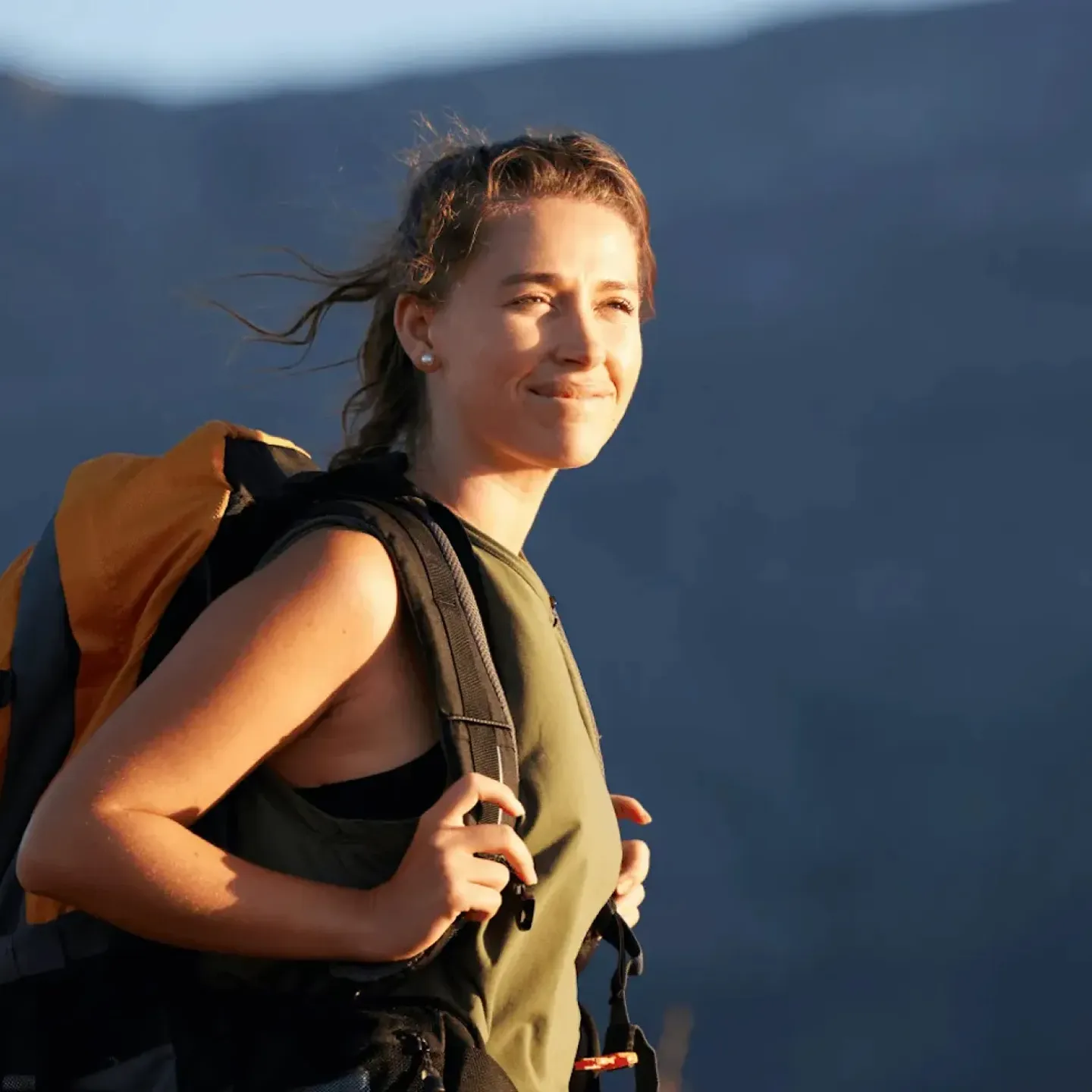 Content woman wearing a backpack outdoors, representing comfort with travel and pelvic health.