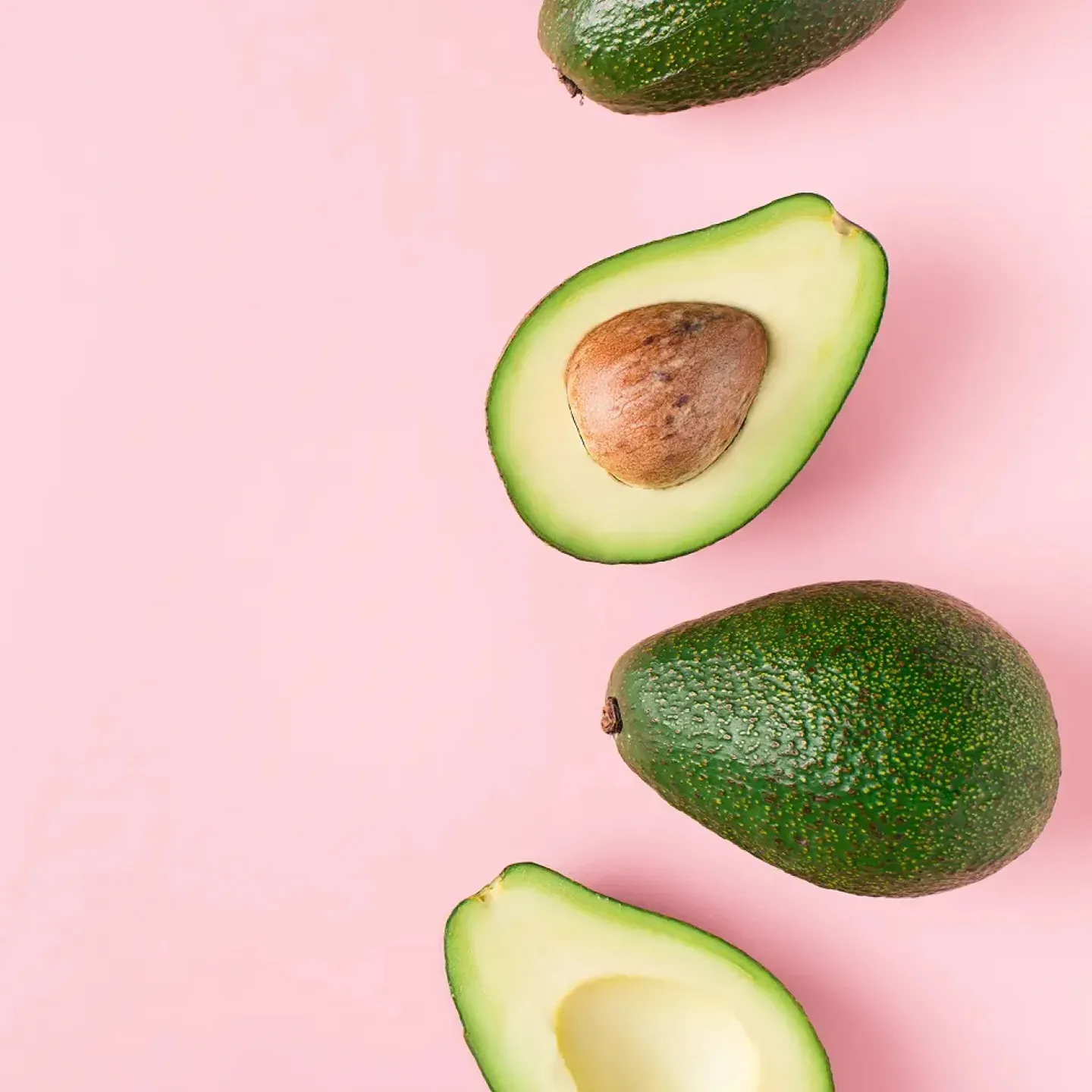 Avocados on a pink backdrop representing Diet to Gain Muscle Mass for women.