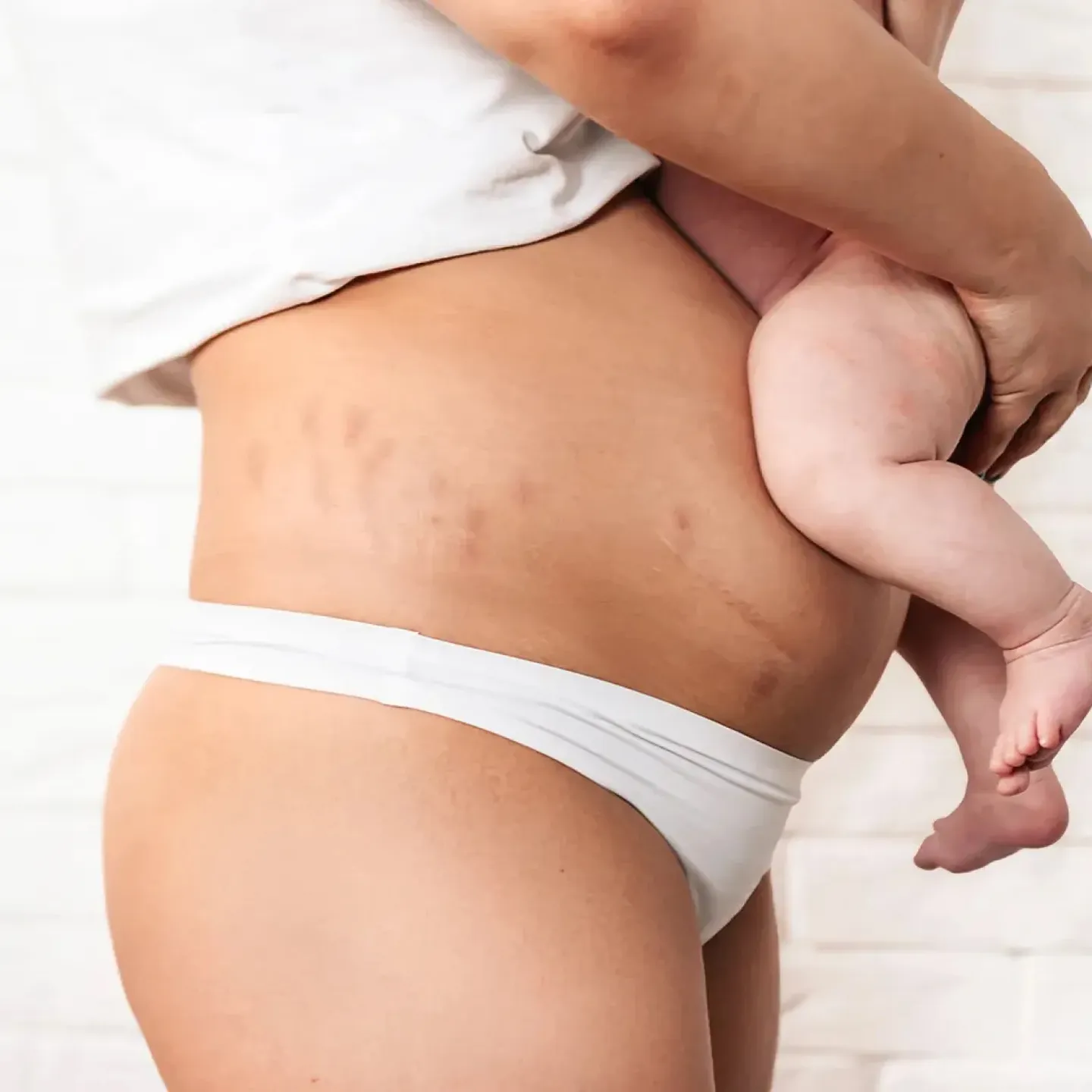 New mother holding her baby, representing the postpartum recovery milestones nobody talks about.