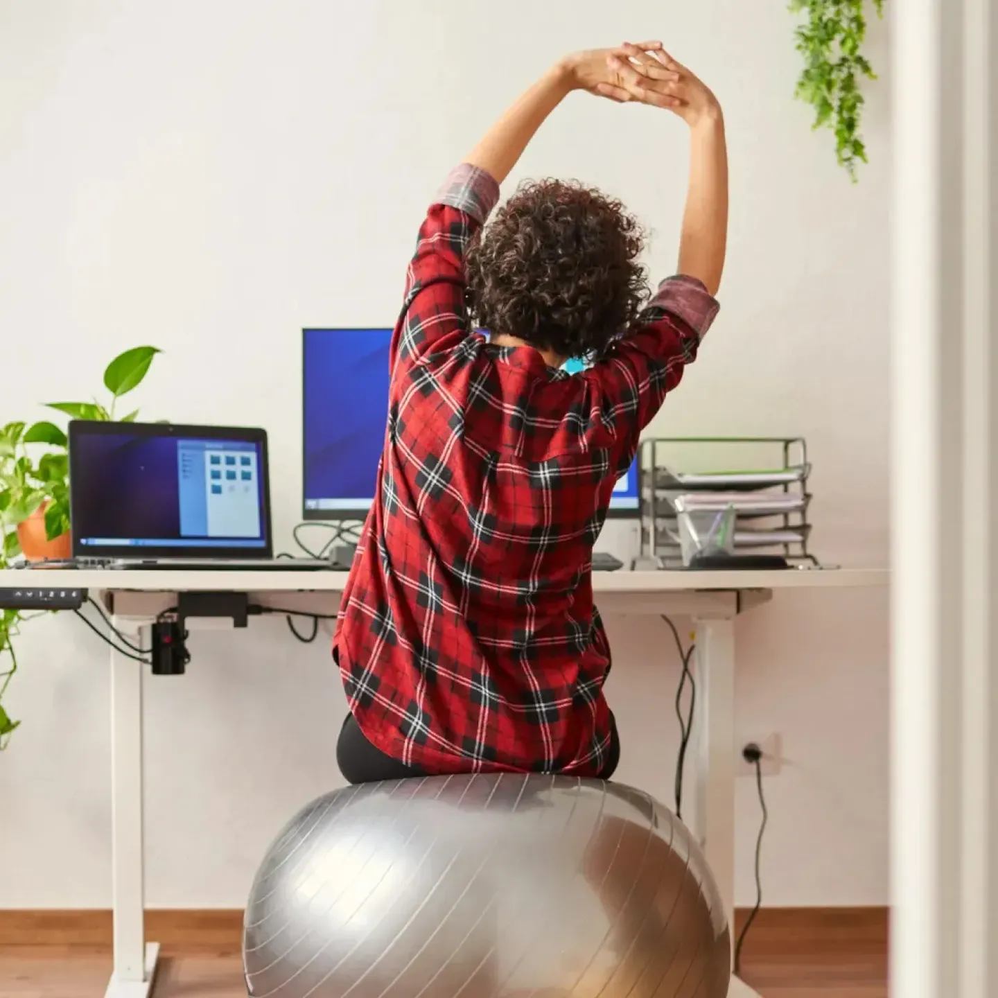 Woman sitting at her ergonomic workstation and doing exercises to support her physical and pelvic health.