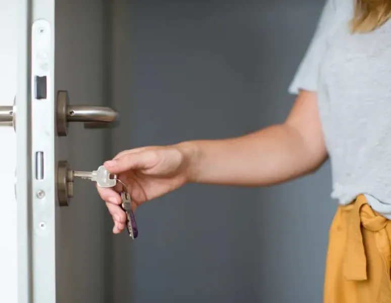 Woman with latchkey incontinence who needs to go to the bathroom as she is opening the door.