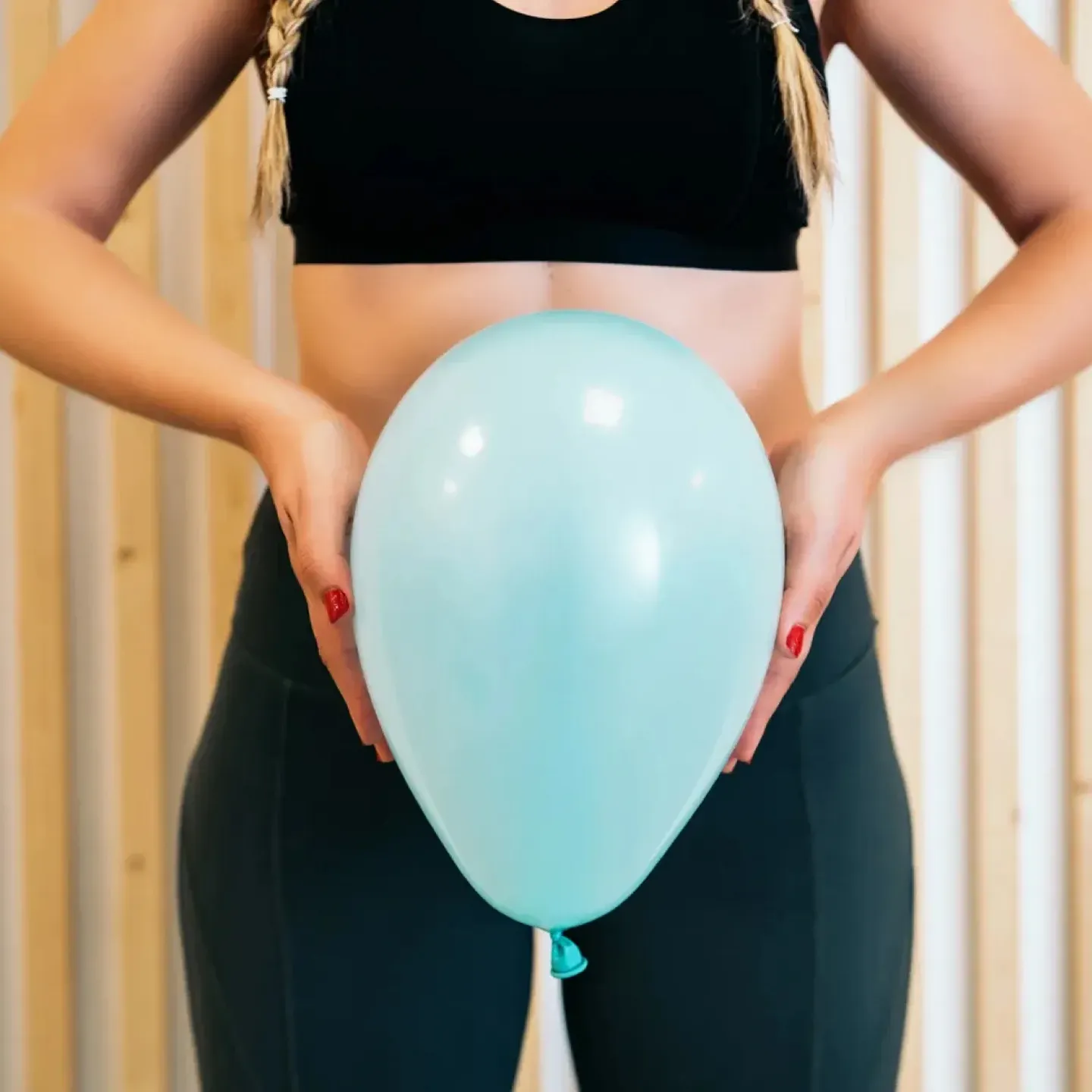 Woman holding inflated balloon in front of her pelvis, representing pelvic floor function what's normal and not normal.