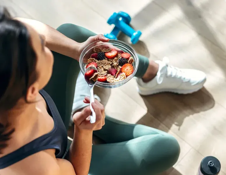 Woman in exercise clothes eating foods to help her joint health.