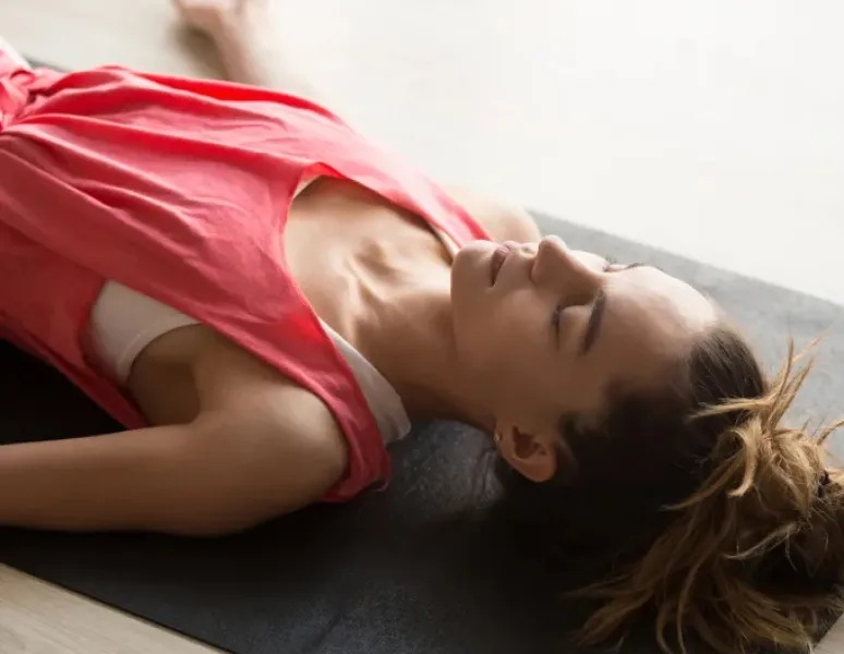 Woman laying on her back resetting her nervous system with box breathing exercise.