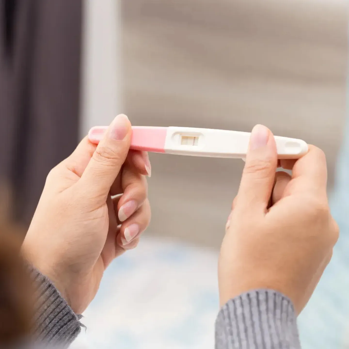 Woman trying to conceive holding pregnancy test representing a guide to preparing to conceive.