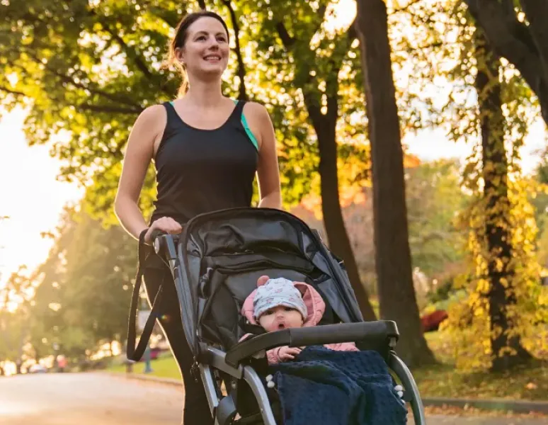Woman returning to running postpartum after pelvic floor therapy, on a run with her baby in a jogger.