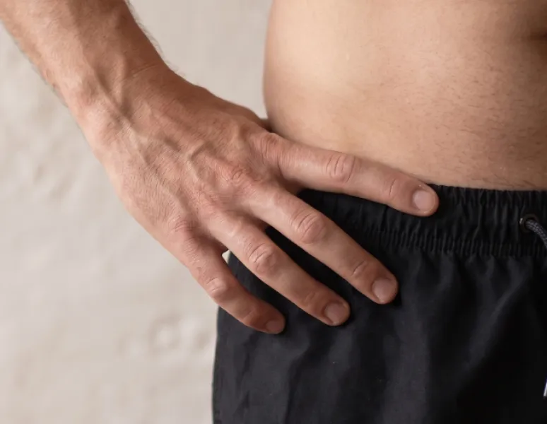 Zoomed in photo of man with a hand on hip, representing male pelvic health: male pelvic floor dysfunction, common symptoms, and how pelvic floor physical therapy.