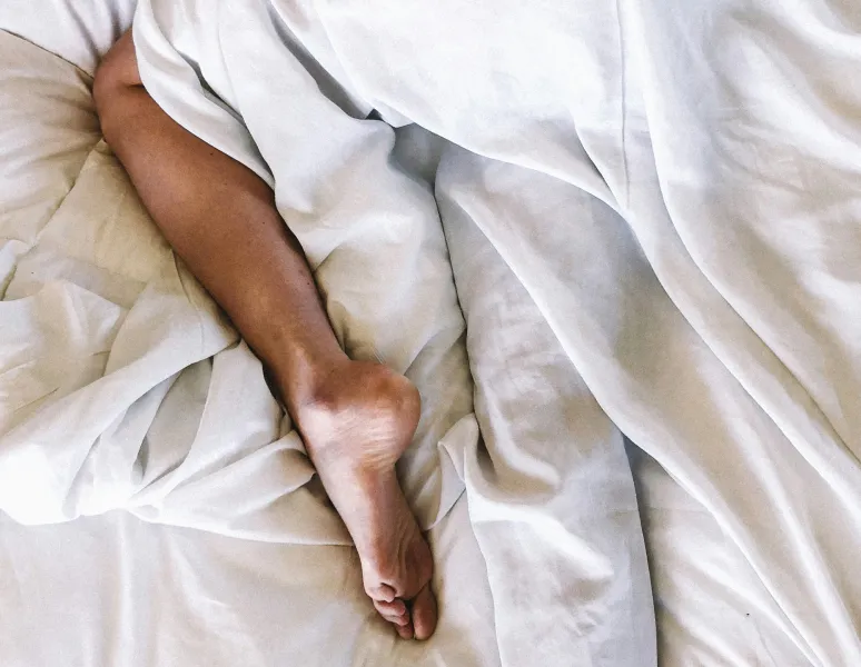 Image of person's legs laying in bed, representing painful sex.