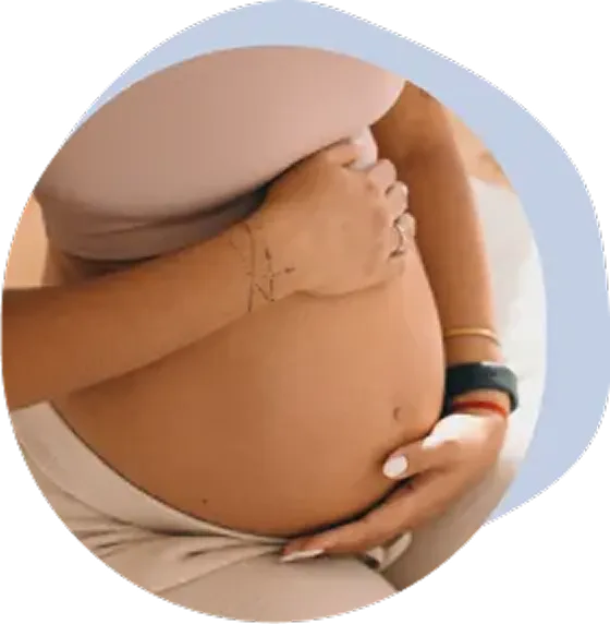 A close up of a woman holding her pregnant belly before getting pelvic floor physical therapy.