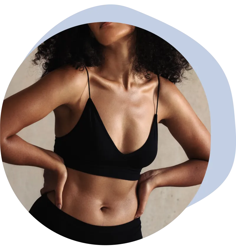 Un primer plano de una mujer en ropa interior negra flexionando sus músculos abdominales.