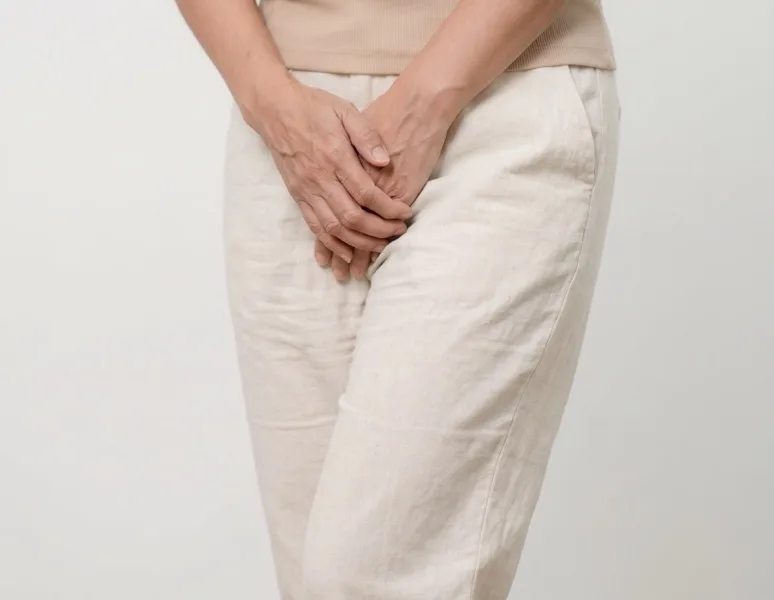Woman holding her hands over her pelvis, representing bladder leaks when you sneeze.