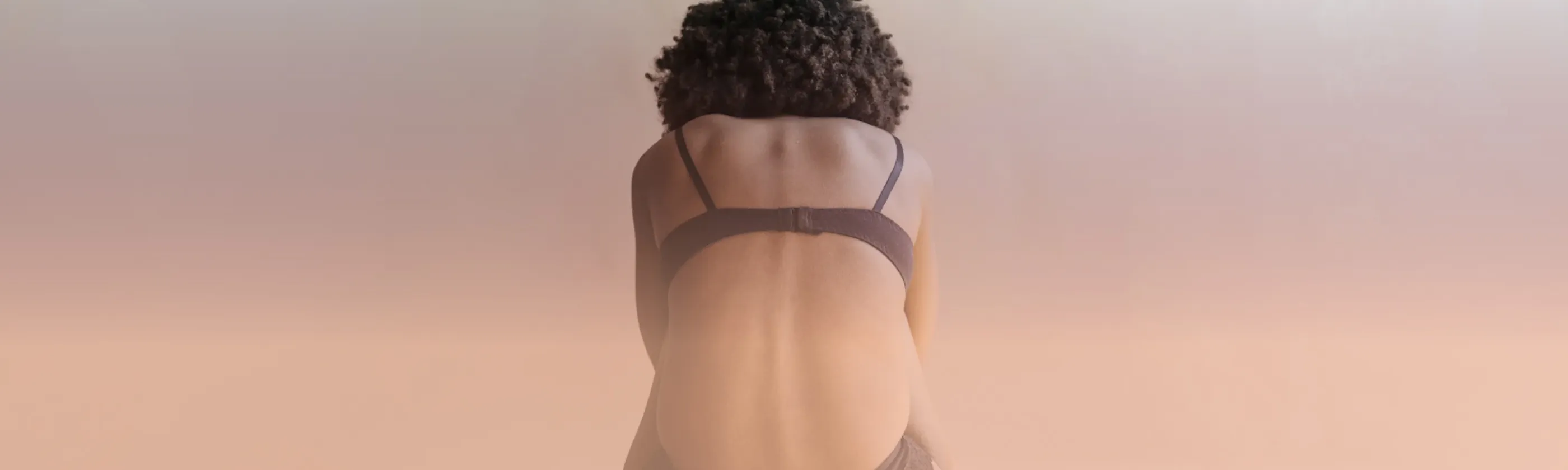 A woman sitting on the floor, bent foward in pain.