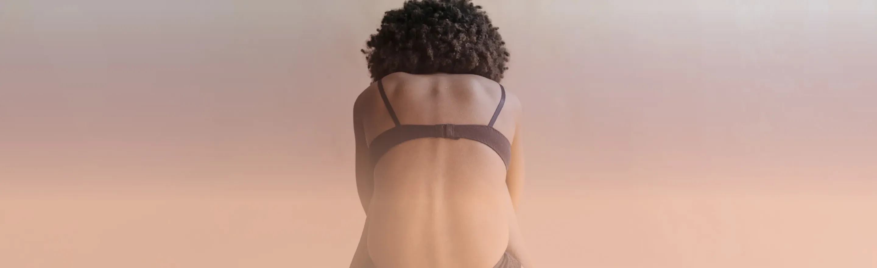A woman sitting on the floor, bent foward in pain.