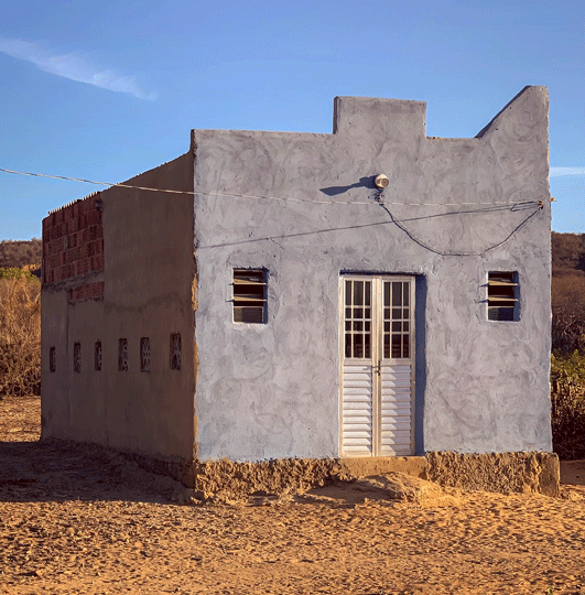 Ein kleines blaues Haus auf dürrem Boden