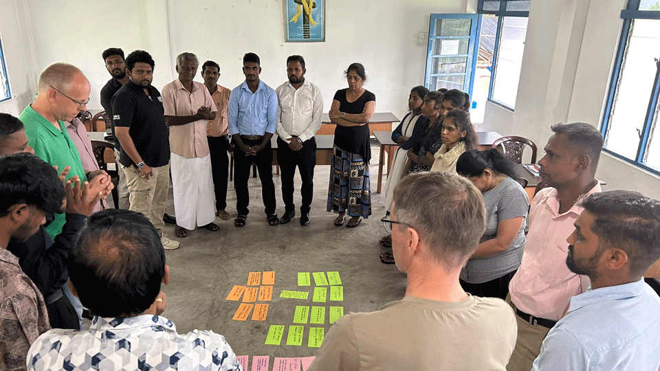 Andreas et David se tiennent en cercle avec un groupe d'étudiants, des feuilles de couleur sur le sol