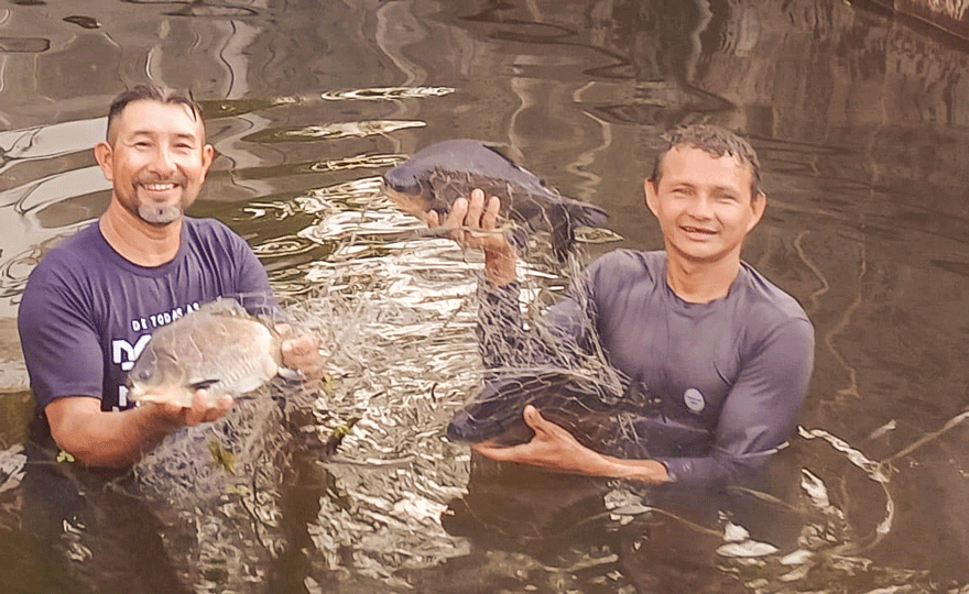 Deux hommes se tiennent dans l'eau et tiennent ensemble un gros poisson
