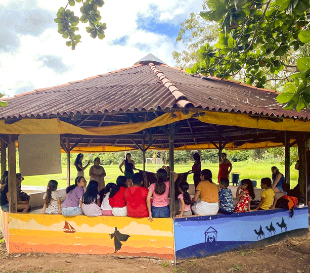 Un groupe de personnes est assis dans un pavillon aux parois ouvertes.