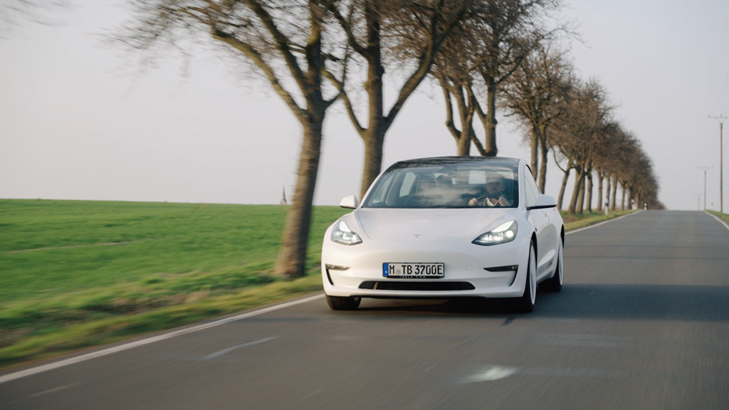 Ein weißes E-Auto fährt auf einer Landstraße