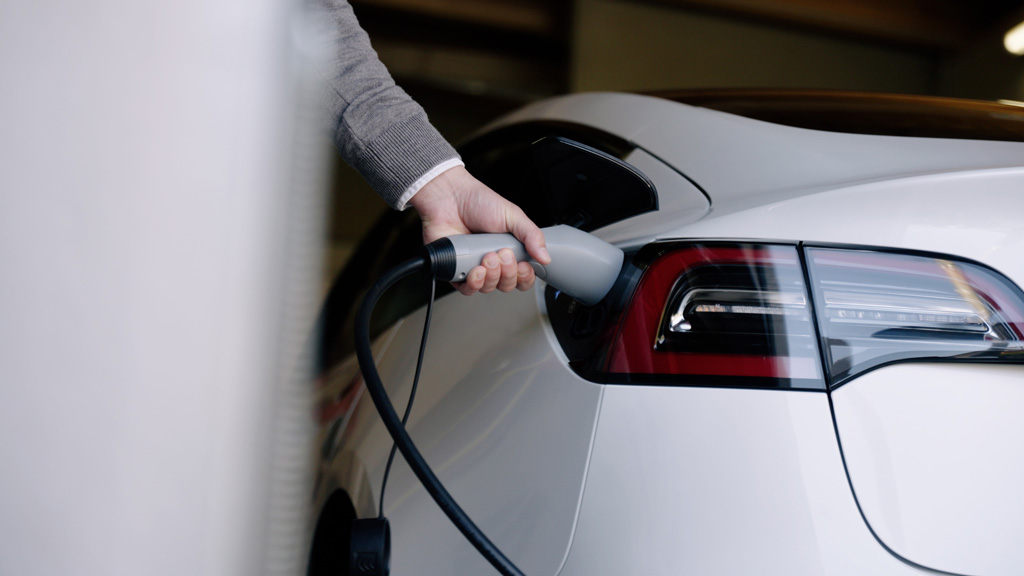 Ein Ladekabel wird in ein E-Auto gesteckt