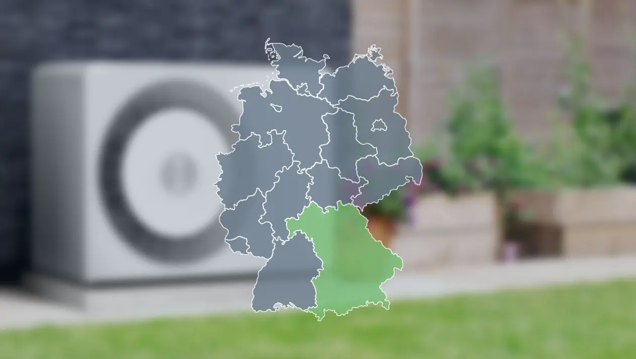Wärmepumpe verschwommen im Hintergrund und Deutschlandkarte im Vordergrund, wo Bayern grün markiert ist, um die Wärmepumpenförderung dort zu zeigen