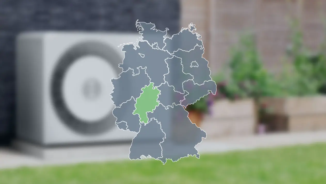 Wärmepumpe verschwommen im Hintergrund und Deutschlandkarte im Vordergrund, wo Hessen grün markiert ist, um die Wärmepumpenförderung dort zu zeigen