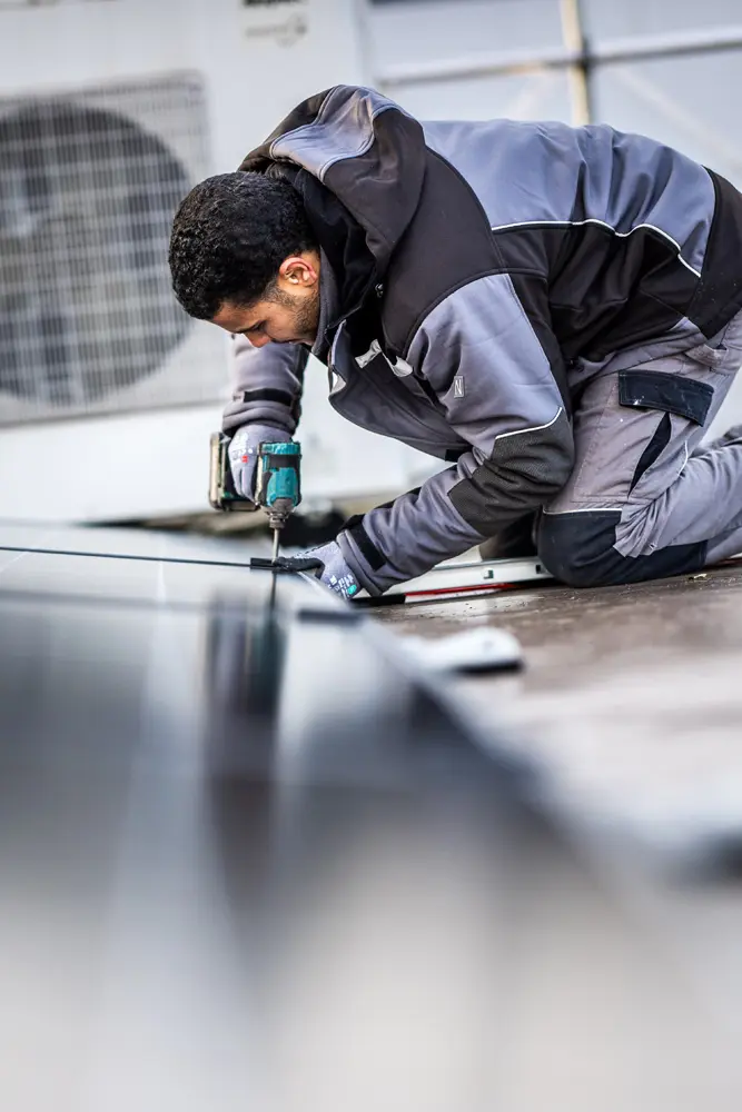ɫý Handwerker montiert Solarmodule auf einem Dach eines Gewerbekunden