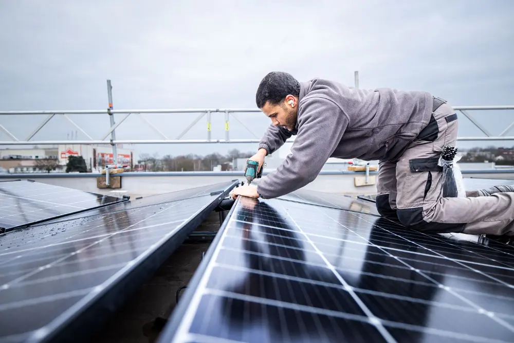 Enpal Handwerker montiert Solarmodule auf einem Dach eines Gewerbekunden