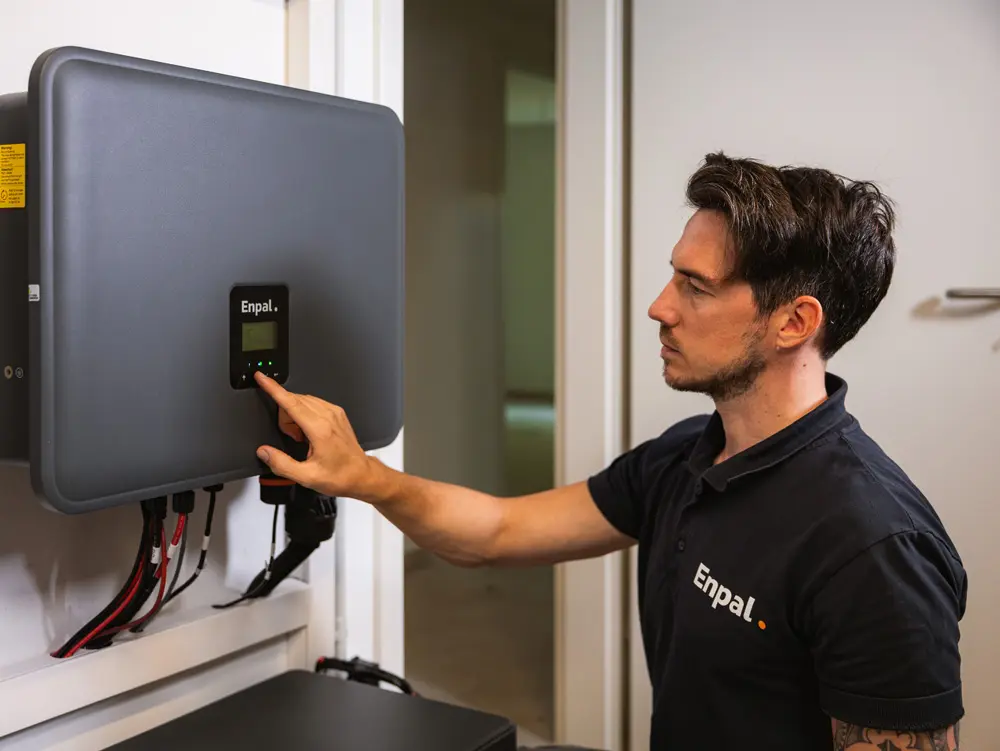 Enpal-Monteur mit einer Hand am Wechselrichter