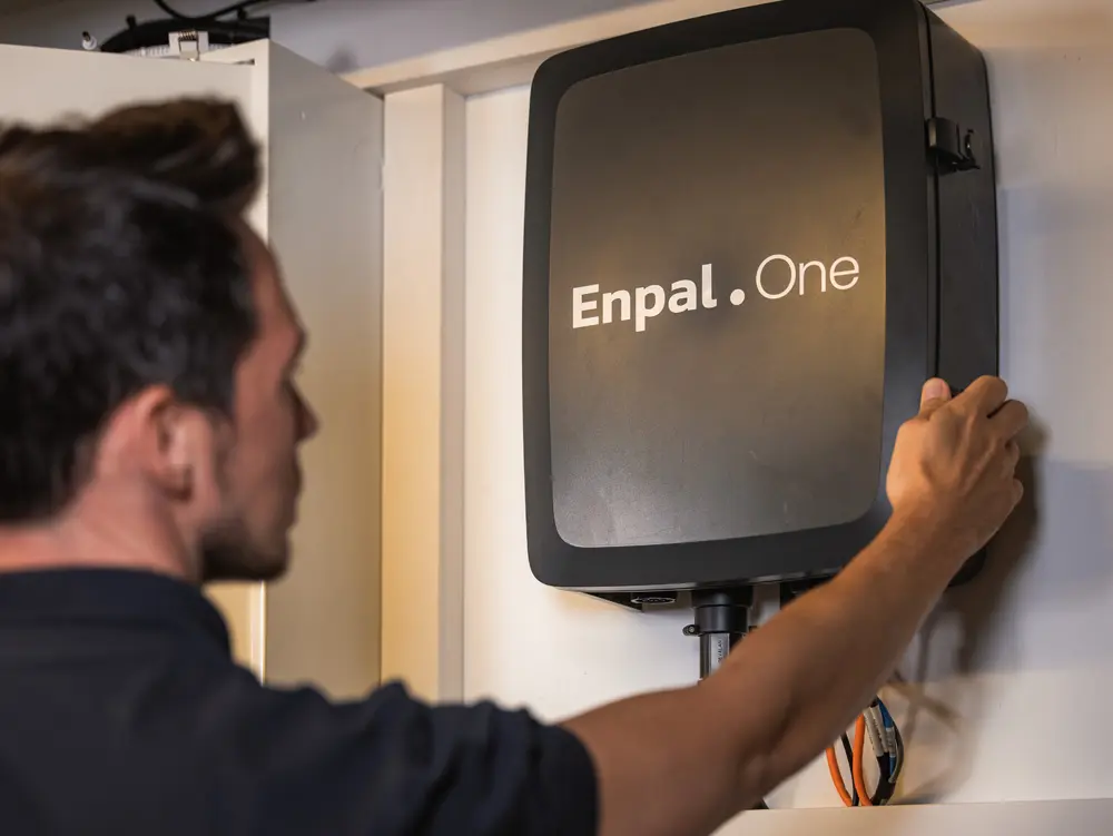 Enpal-Monteur mit einer Hand am Energiemanager Enpal.One