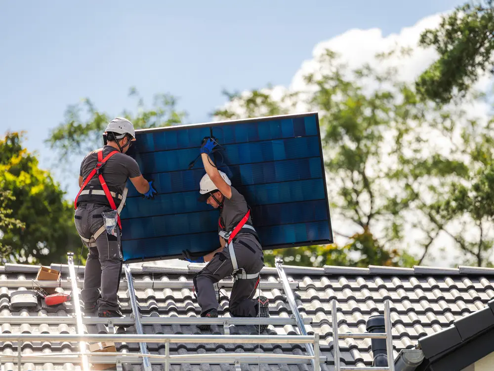 Zwei Enpal-Monteure mit einem Solarmodul auf einem Dach