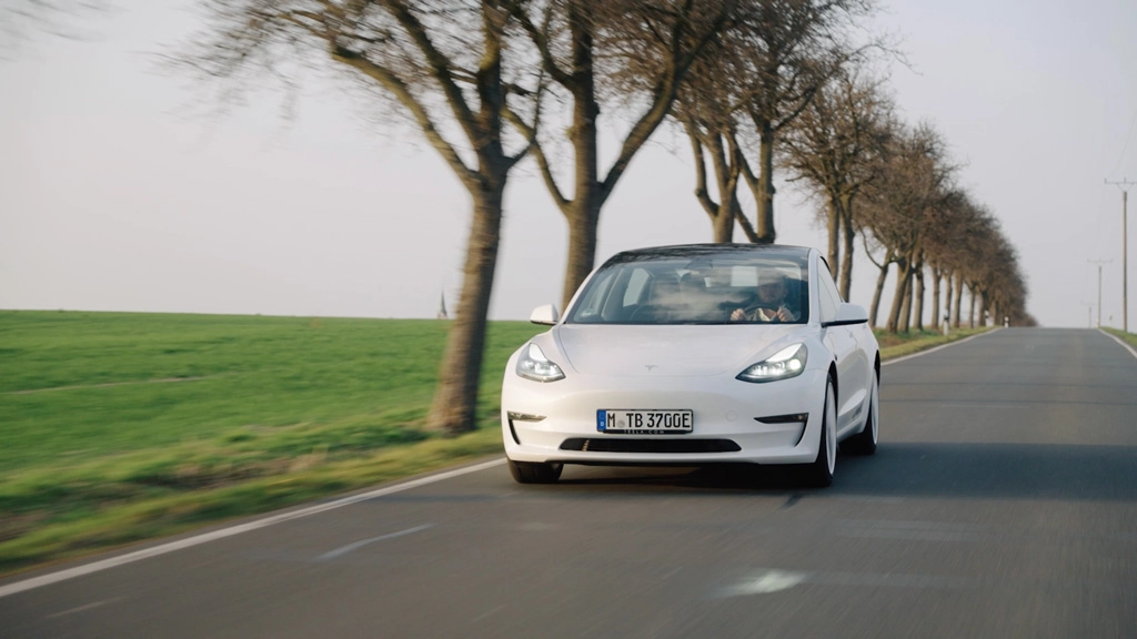 Ein weißes E-Auto fährt auf einer Landstraße