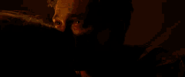 a close up of a man 's face with a woman 's face in the background