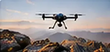 Quadcopter drone in flight above a mountain ridge at sunset