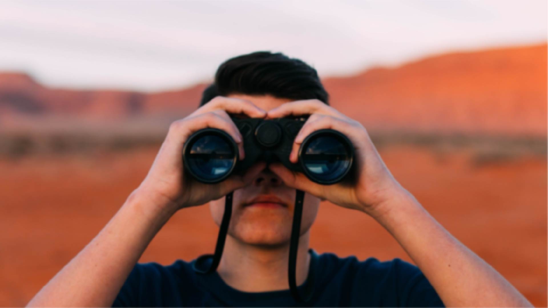 Immagine di un uomo che guarda con un binocolo nel deserto