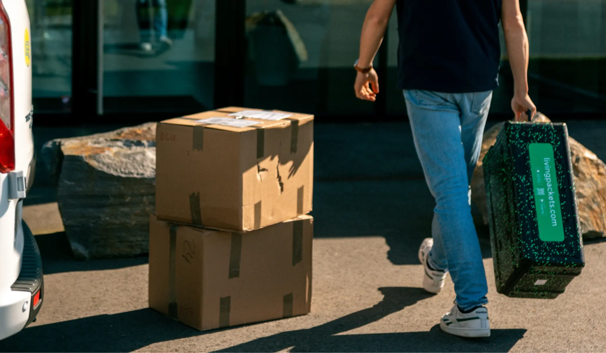 One person holding THE BOX with two cardboard boxes next to it