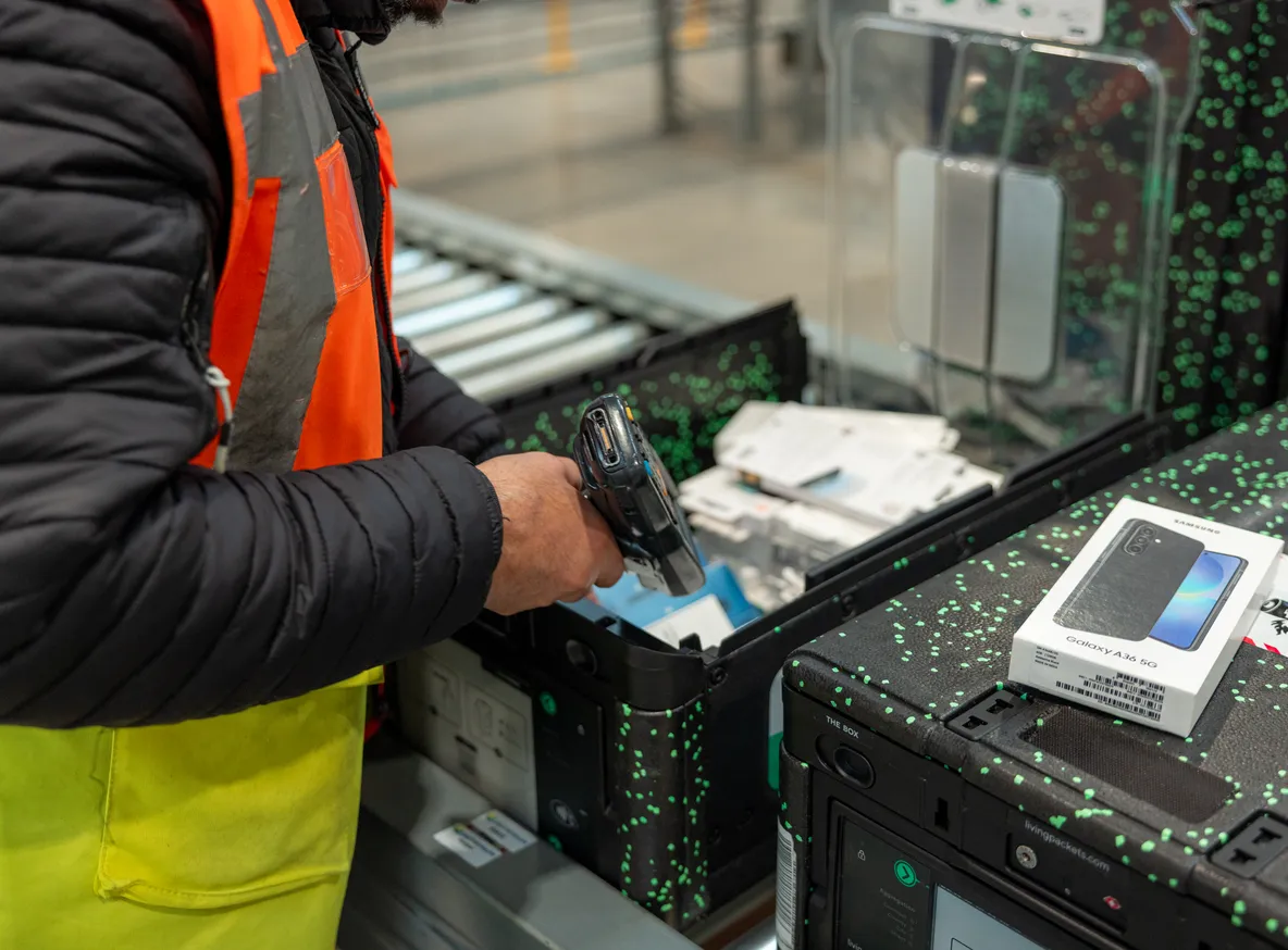 Logisticians preparing high-value electronic parcels in a secure warehouse, illustrating premium packaging, traceability, and logistics operations.
