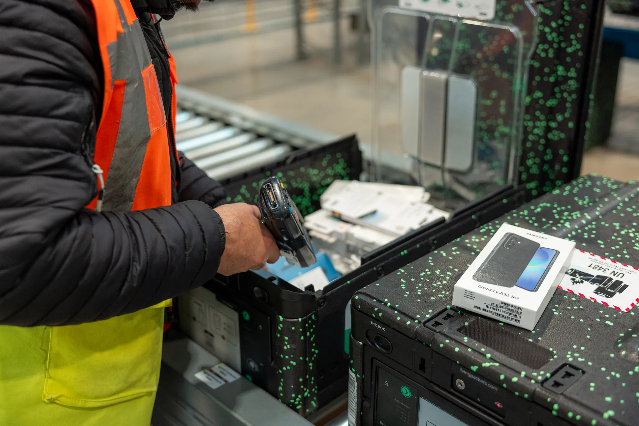 Logisticians preparing high-value electronic parcels in a secure warehouse, illustrating premium packaging, traceability, and logistics operations.