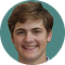 Smiling young man with short brown hair against a teal circular background.