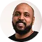 Smiling man with beard wearing a black shirt against a white background.