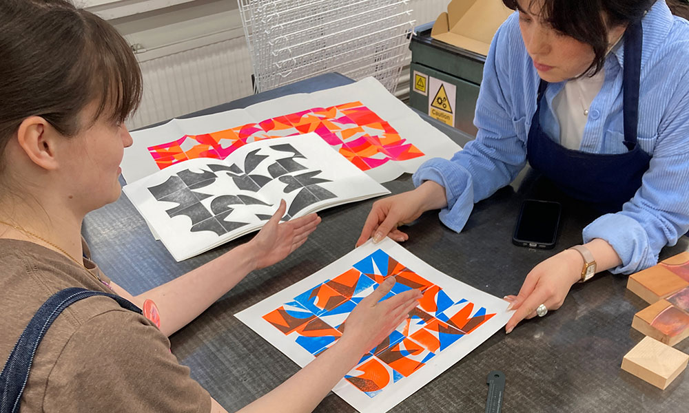 A student and technician discuss the letterpress process over one of the printed outcomes.